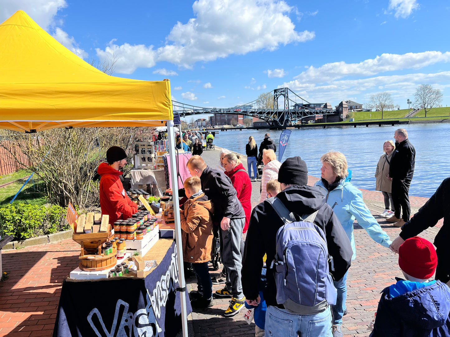 Personen am Verkaufsstand, im Hintergrund die Kaiser-Wilhelm Brücke